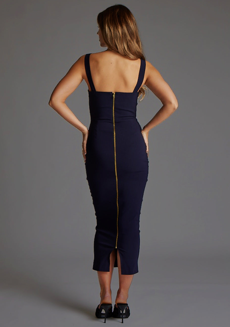Back image of a model wearing the VSPR Jennica Navy Midaxi Dress highlighting the smooth stretch fabric centre back gold zip and curve-enhancing bodycon fit.