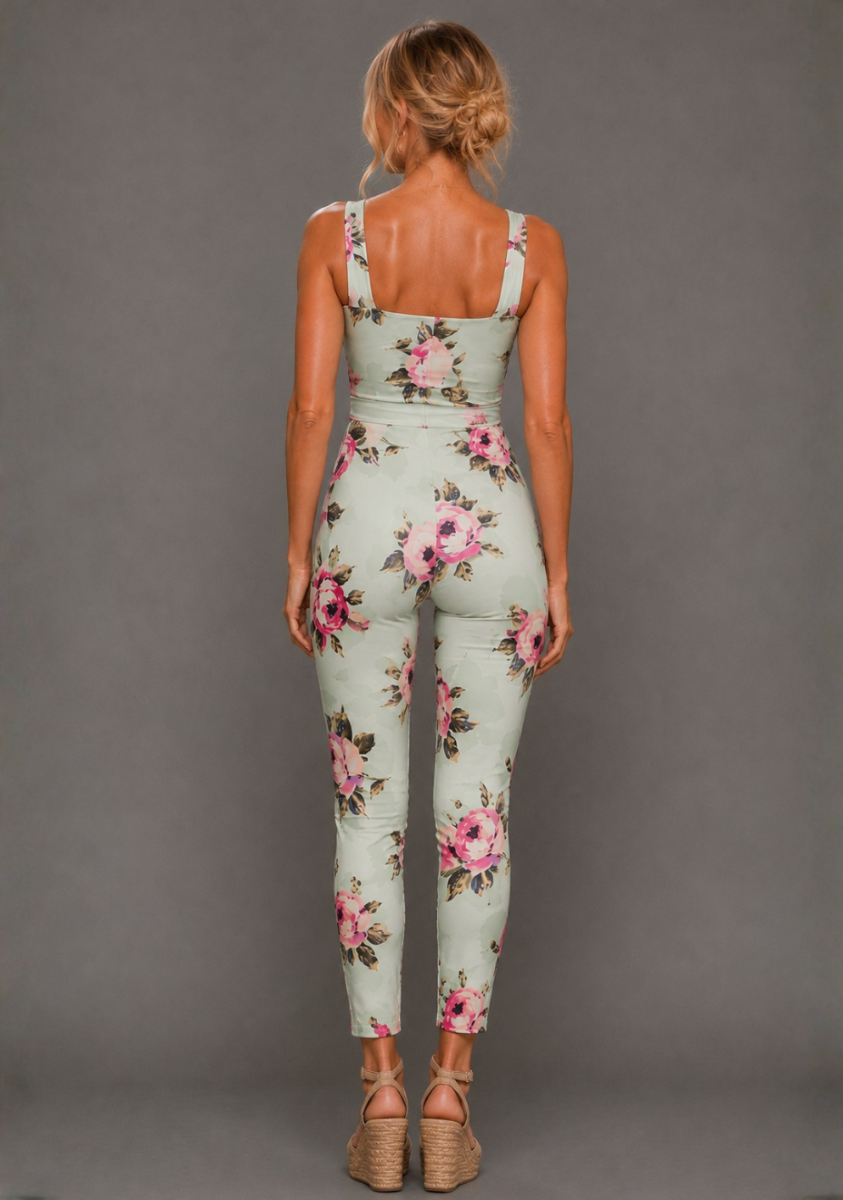 Back image of a model wearing the VSPR Nala Square Neckline Mint Floral Jumpsuit in Mint Floral with a self-tie waist belt and sleek tapered legs, standing against a grey studio backdrop.