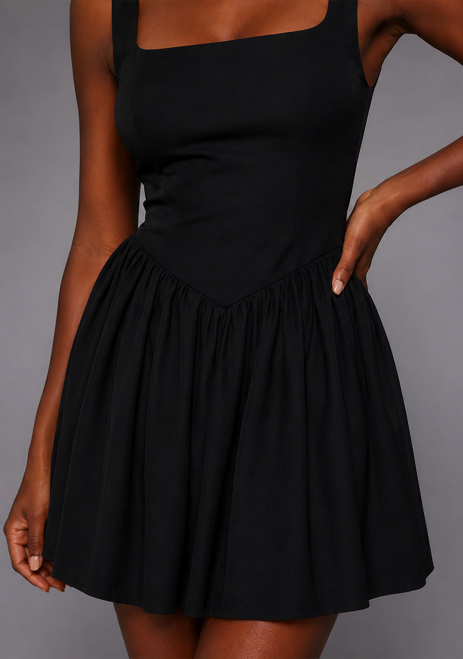 Close-up image of the VSPR Sofia Square Neck Skater Skirt Black Mini Dress showcasing the structured square neckline, wide shoulder straps, and premium stretch luxe fabric against a grey studio backdrop.
