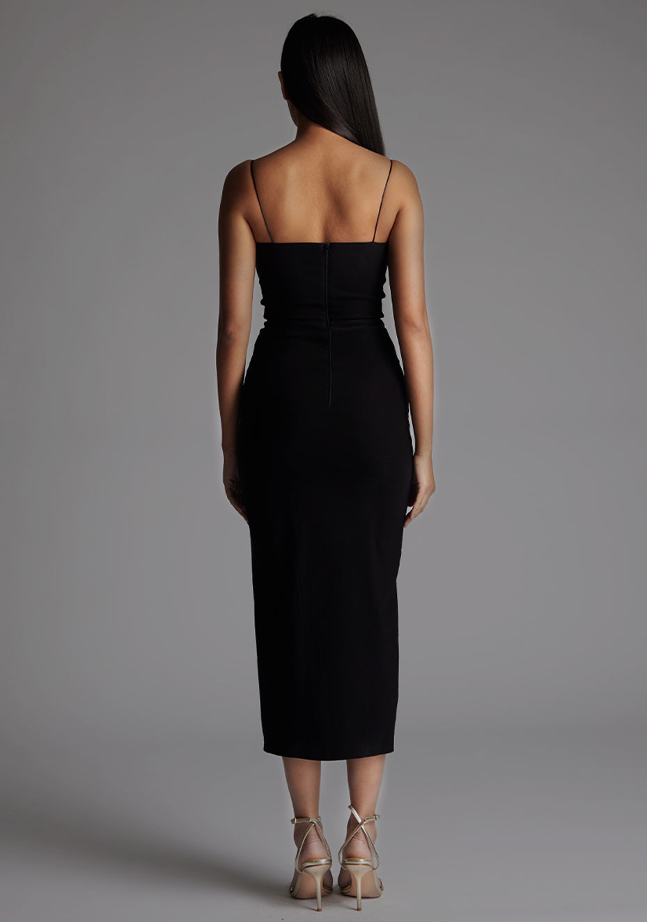 Back image of a model wearing the Vesper Adeline Cut Out Midaxi Dress in Black, displaying the slim straps, fitted waist, and sleek midaxi length.