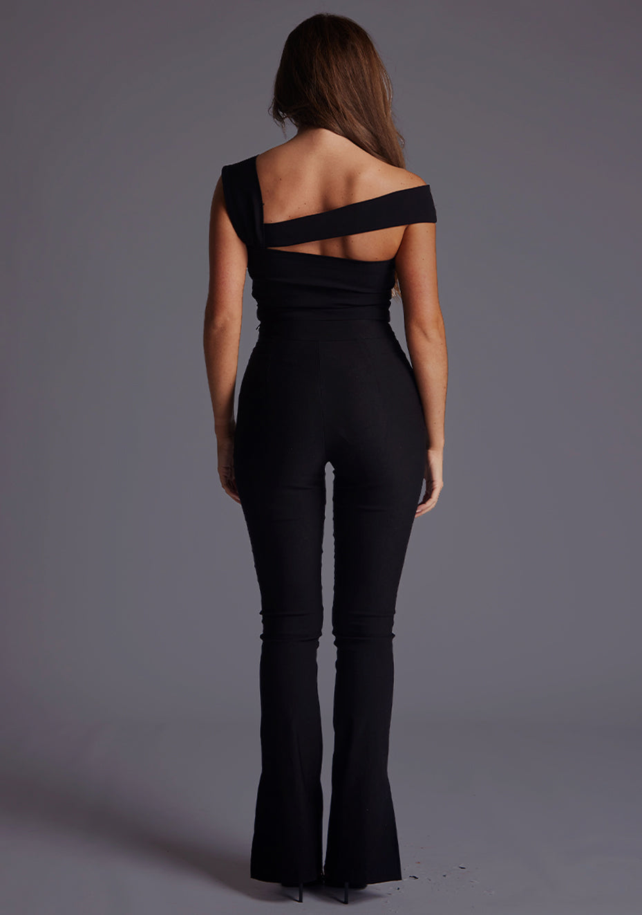 Back image of a model wearing the Vesper Angel Asymmetric Neckline Top in Black, displaying a clean, minimal back design with a smooth, sculpted silhouette.
