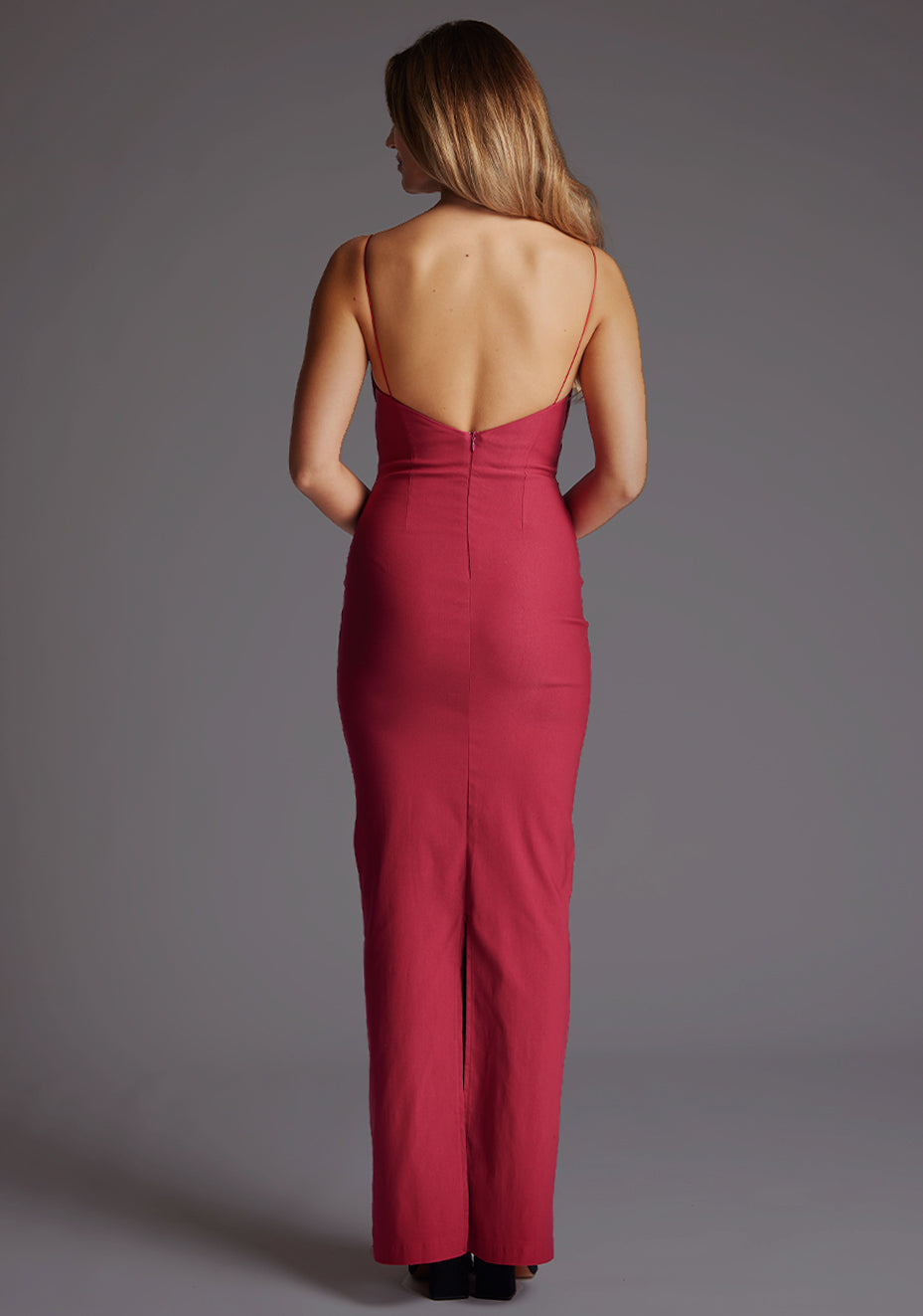 Back image of a model wearing the Vesper Bellini Cami Strap Bow Maxi Dress in Raspberry, featuring a sleek open back design, delicate straps and timeless maxi shape.
