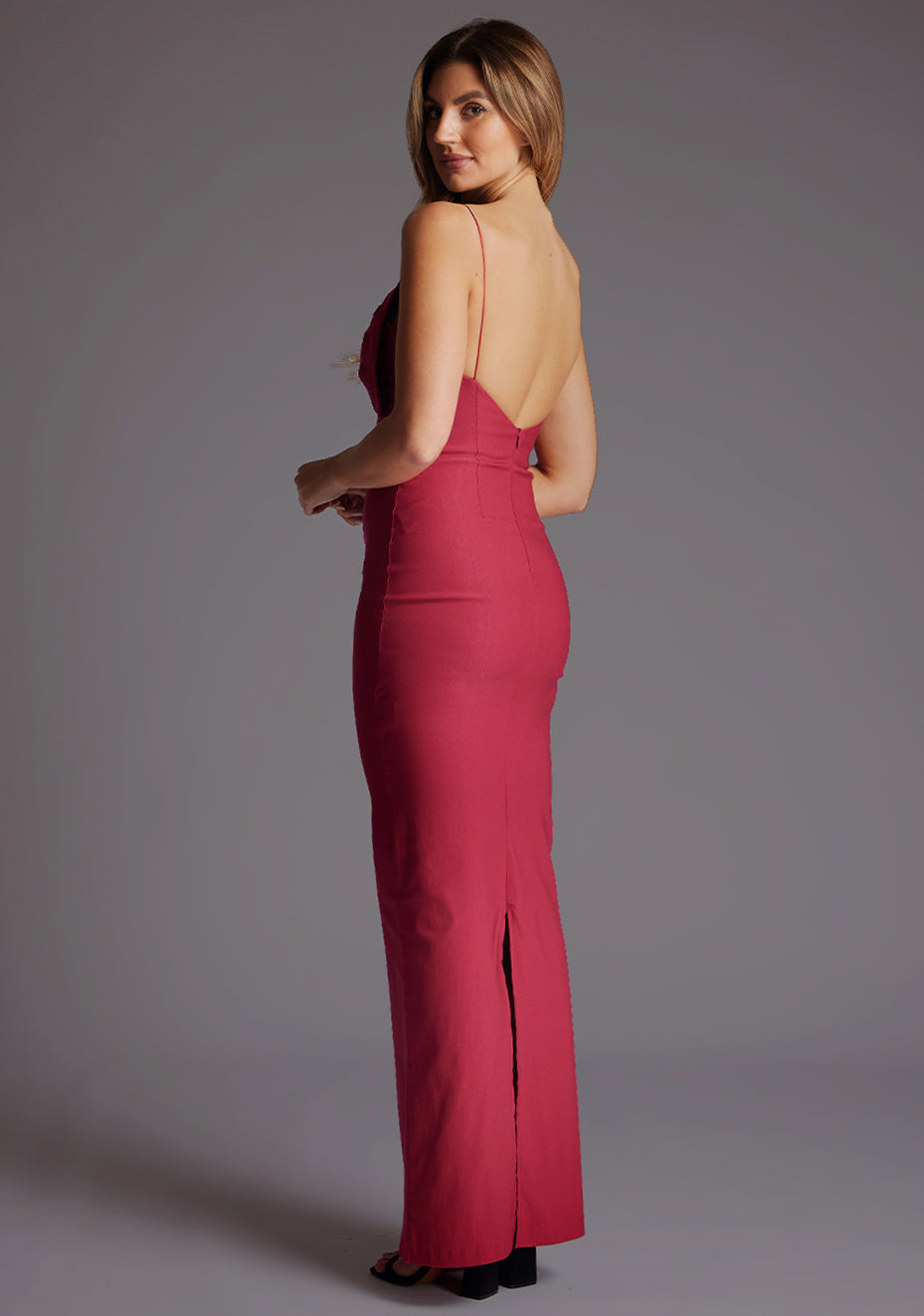 Side back image of a model wearing the Vesper Bellini Cami Strap Bow Maxi Dress in Raspberry, revealing the delicate strap placement and smooth flowing back silhouette.