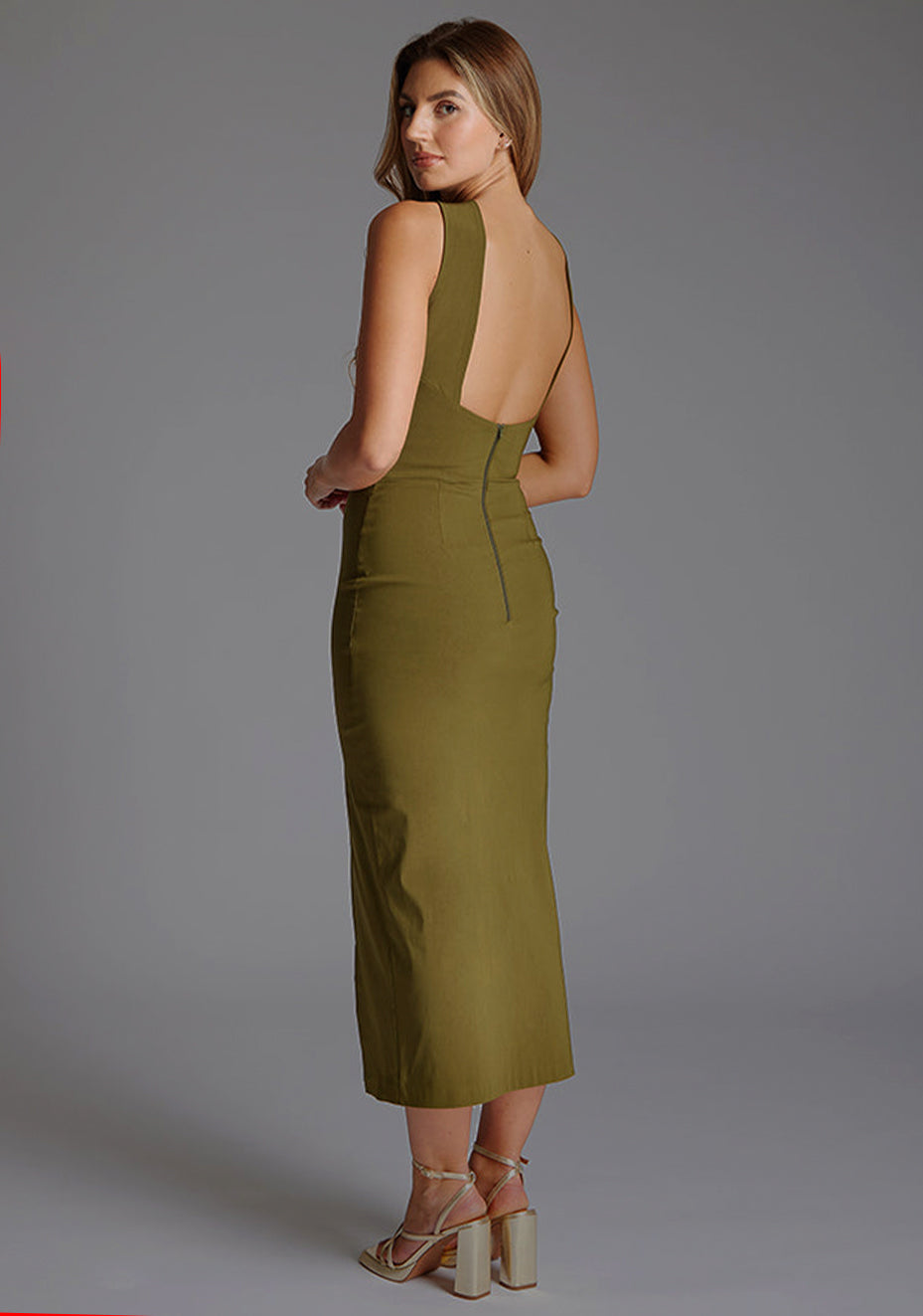 Side back image of a model wearing the Vesper Carter Halterneck Bodycon Midaxi Dress in Olive, revealing the sleek back profile and smooth finish.