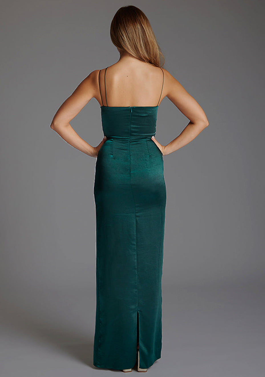 Back image of a model wearing a pine green maxi dres with a chic thin straps and featuring a tasteful ruched design and complete with a convenient back zip. The design featured is the Vesper Lorah Satin Drape Maxi Dress in Pine Green.
