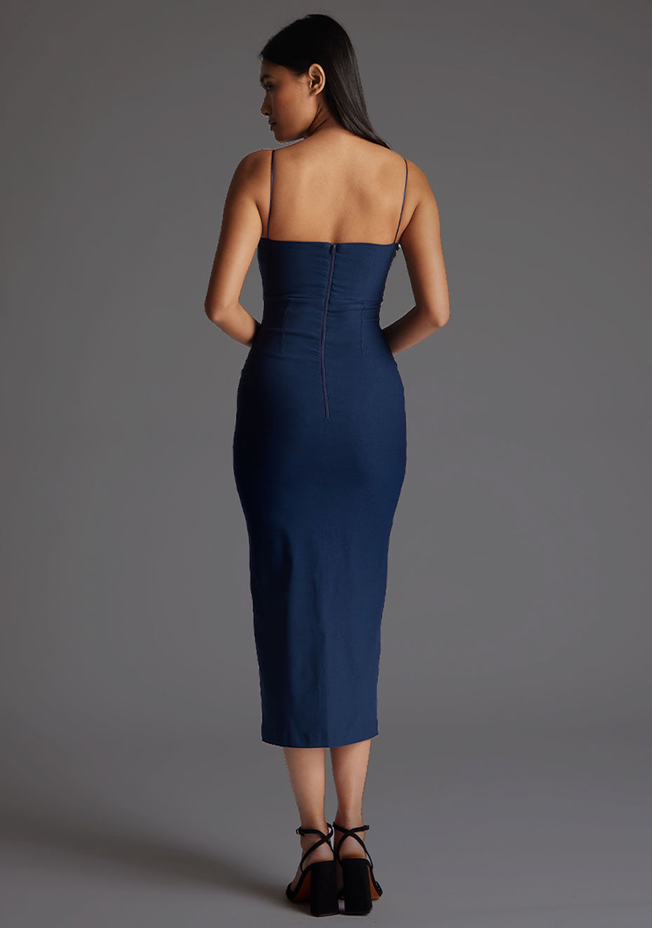 Back image of model wearing a navy strappy midaxi dress with a sweetheart neckline, thin straps, centre front skirt split and centre back zip for a perfect fit. The design featured is the Vesper Miren Strappy Bodycon Midaxi Dress in Navy.