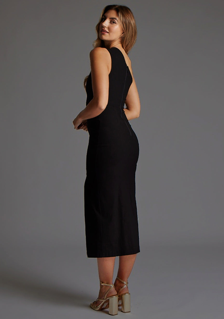 Side back image of the model wearing a Black Midaxi Dress with a asymmetric neckline, one-shoulder design features a tasteful cut out, while the front skirt split adds a chic. The design features Vesper Ollie One Shoulder Cut Out Midaxi Dress With Thigh Split in Black.