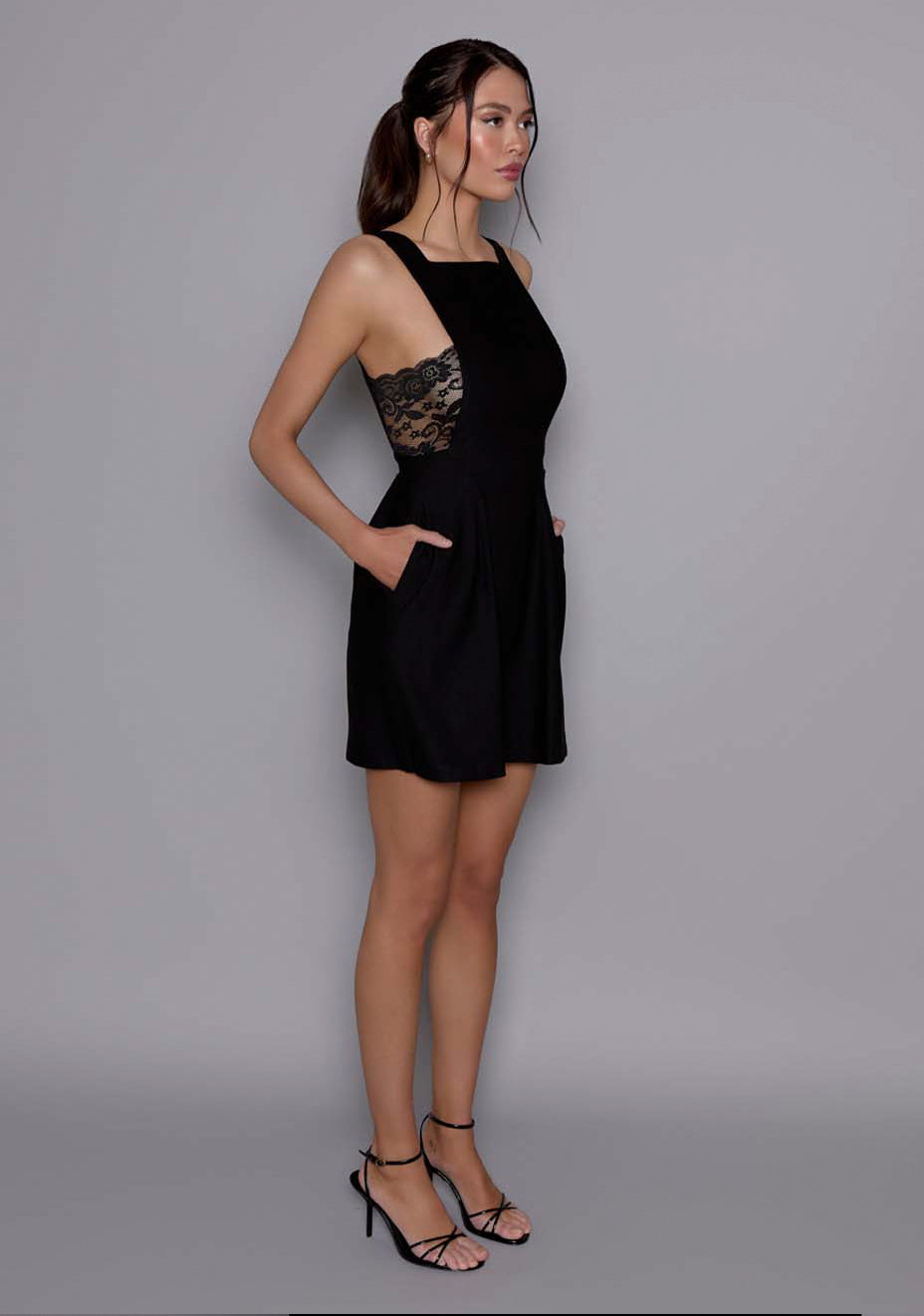 Side-front view of the VSPR Noa Black Mini Dress showcasing the A-line skirt, fitted bodice, and architectural squared neckline.
