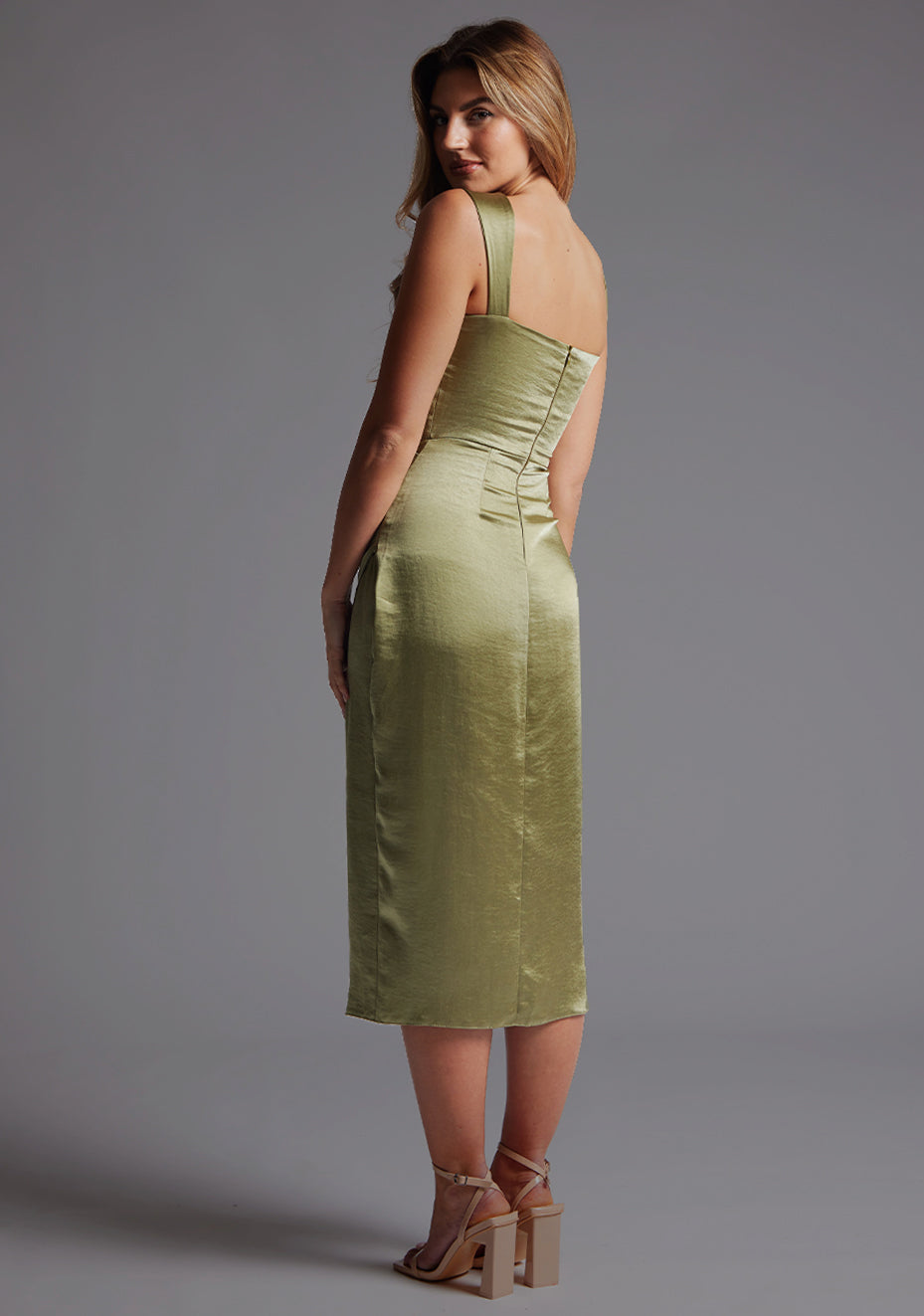 Back quarter image of a model wearing olive satin midaxi dress with a sweetheart neckline, wide comfy straps and front skirt split. The dress featured is the Vesper Desiree Olive Satin Midaxi Dress.