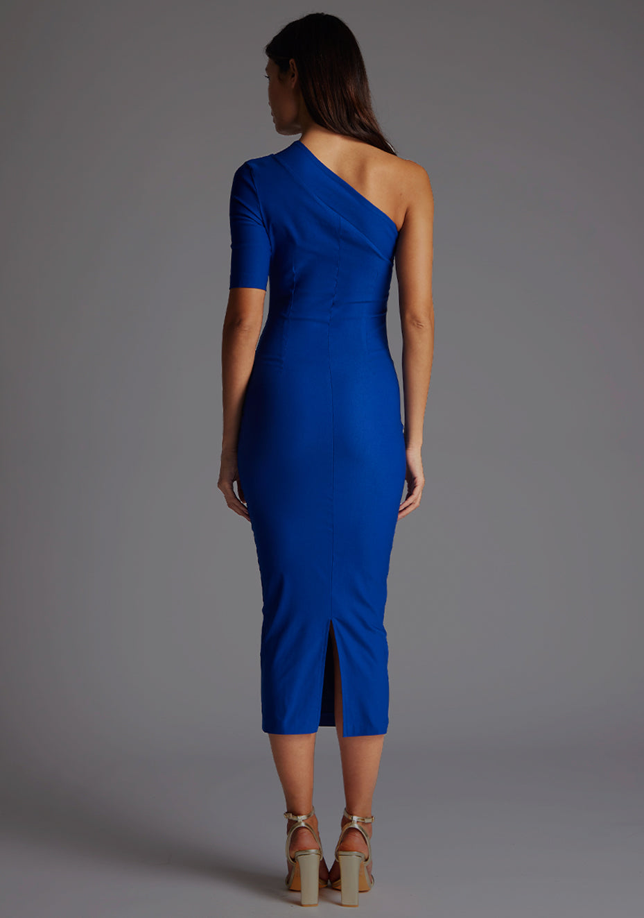 Back image of model wearing a cobalt midaxi dress with a eye-catching asymmetric design with a stunning one-sleeve detail and slim fit enhances your curves and creates a flattering silhouette. The design featured is the Vesper Erin Cobalt Midaxi Dress