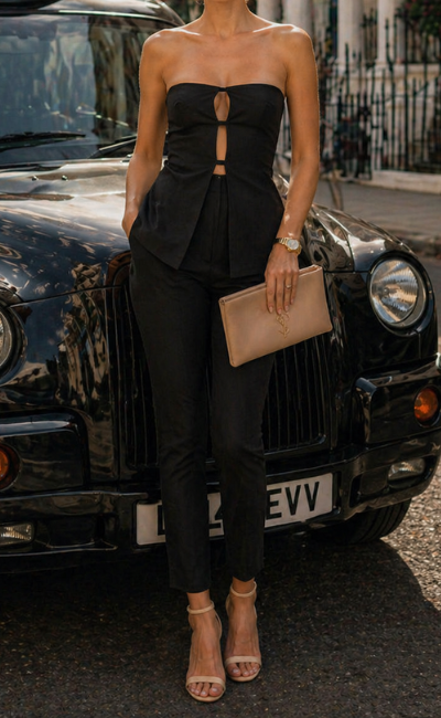 Woman in a black outfit standing in front of a vintage car