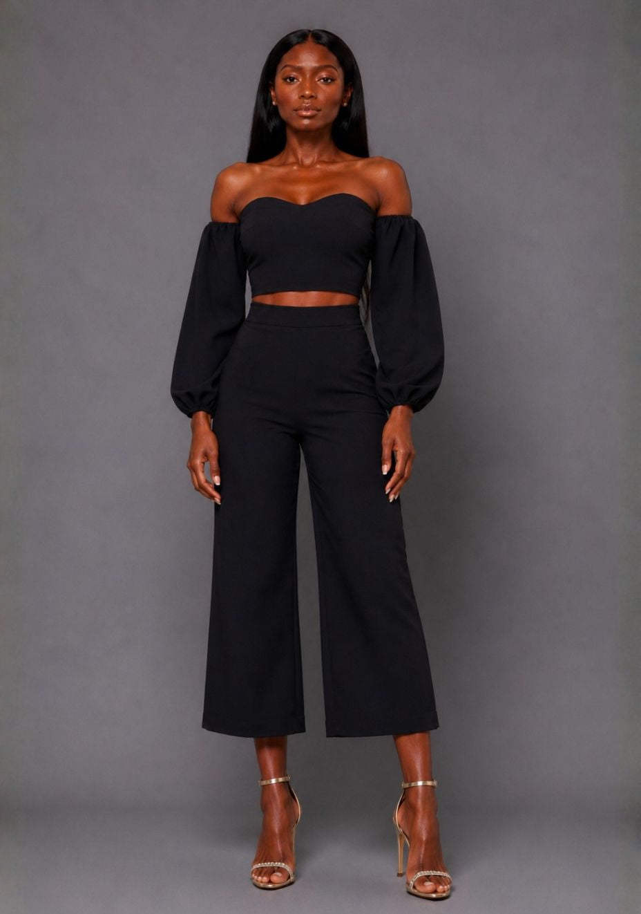 Front image of a model wearing the VSPR Mindi Wide Leg Black Cropped Trousers with a flattering high-rise waist and fluid wide-leg silhouette, standing against a grey studio backdrop