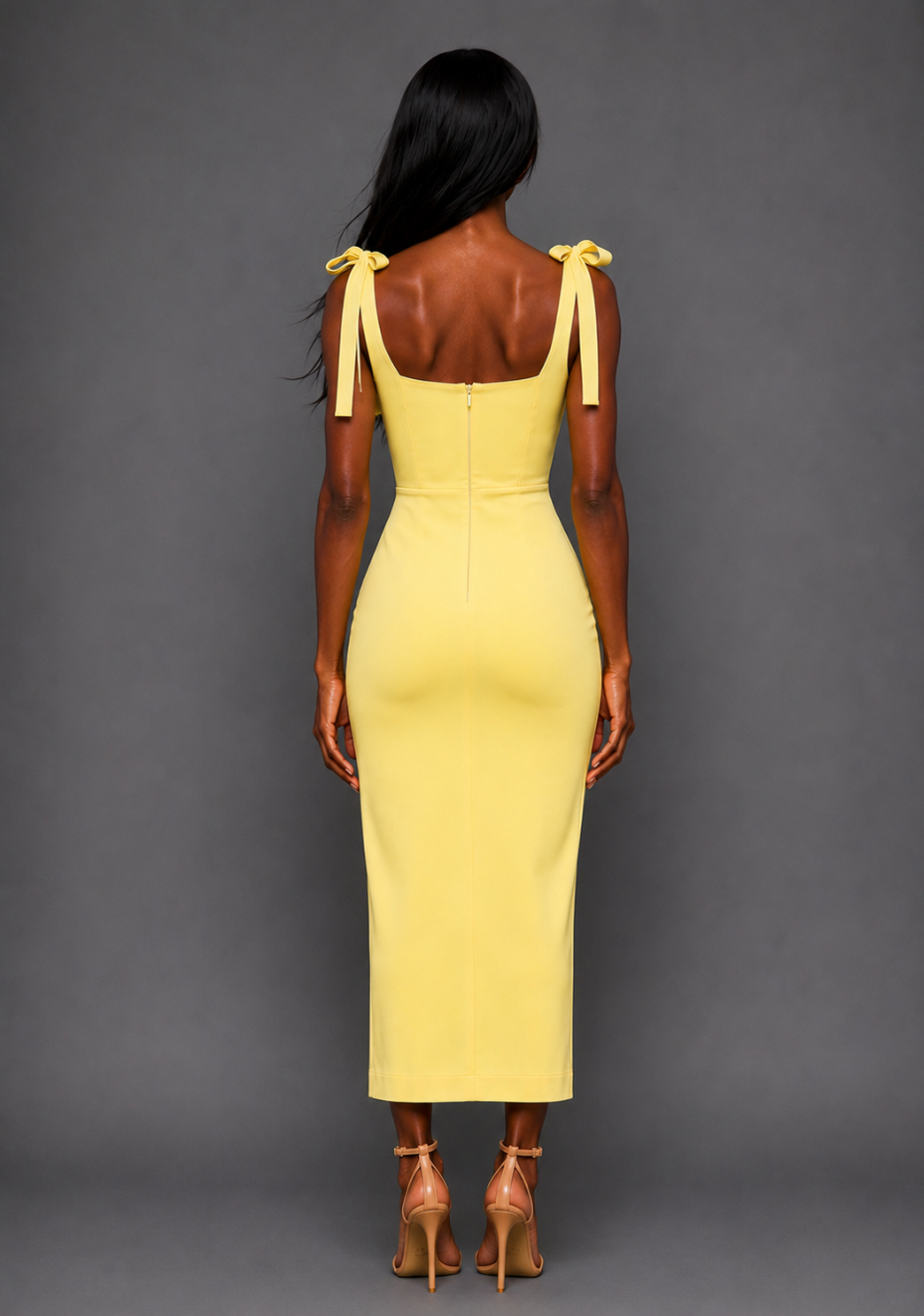 Back image of a model wearing the VSPR Onyx Square Neck Bow Lemon Midaxi Dress in Lemon, highlighting the clean silhouette, delicate adjustable self-tie shoulder straps, and elegant midaxi length against a grey studio backdrop.