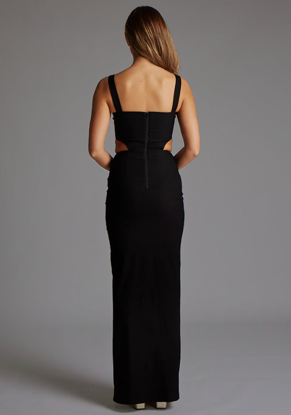 Back image of a model wearing the Vesper Bramley Cut-Out Maxi Dress in Black, featuring a clean minimalist back design, sculpting bodycon fit, and full-length hem.