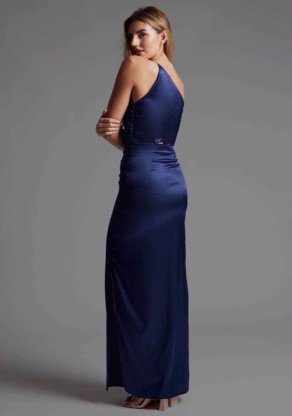 Side back image of a model wearing the Vesper Esme One Shoulder Ruched Satin Maxi Dress in Navy, revealing the smooth back drape and elongated satin silhouette.