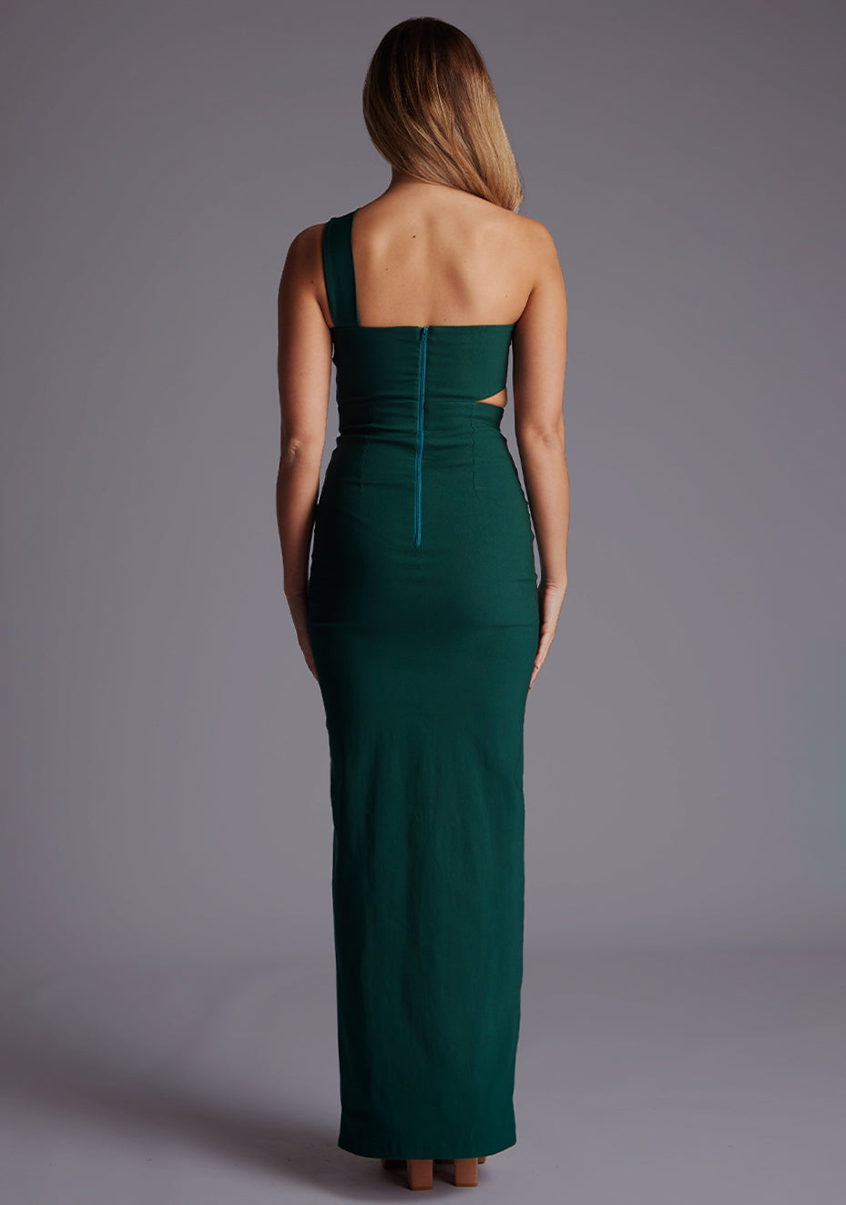 Back image of a model wearing the Vesper Hayden Asymmetrical Maxi Dress in Forest Green, showcasing the sleek back design and elongated maxi silhouette.