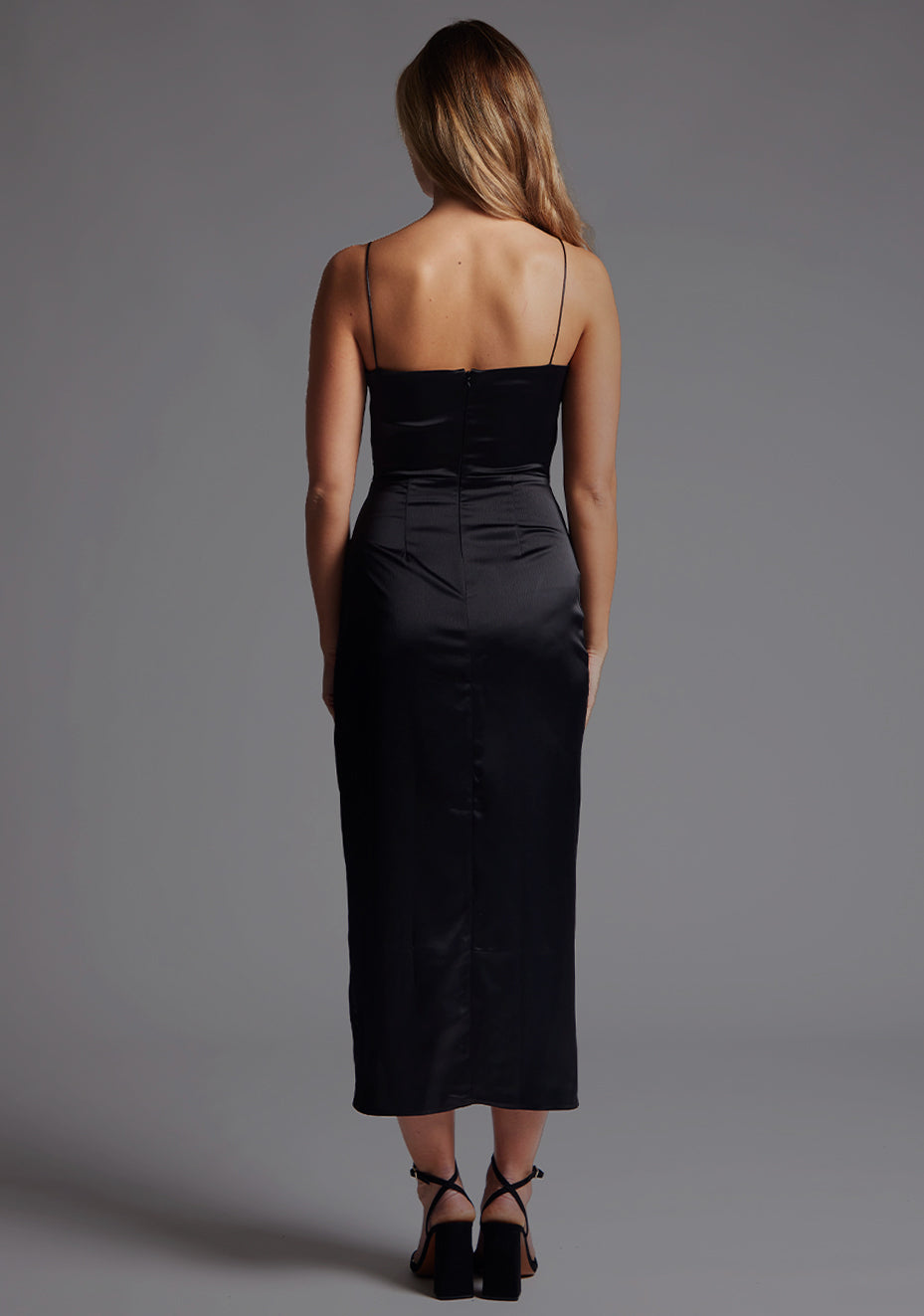Back image of a model wearing the Vesper Margiela Plunge Neckline Midaxi Dress in Black, featuring thin straps and a sleek, fluid midaxi silhouette.