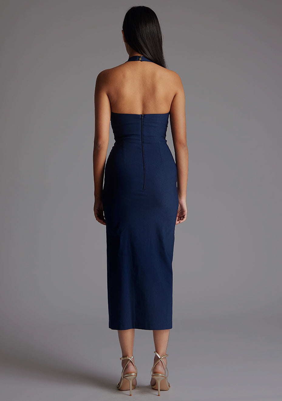 Back image of a model wearing the Vesper Maria Halter Midaxi Dress in Navy, featuring a button fastening and centre-back zip for a seamless finish.