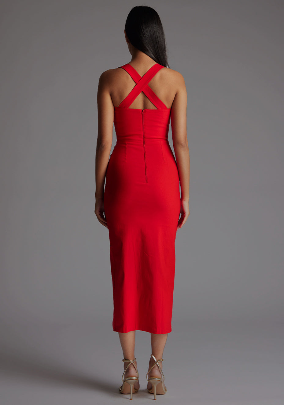 Back image of a  model wearing a red midaxi dress, featuring plunge sweetheart halter neck straps which cross at the back and a front skirt split. The dress featured is the Vesper Poppy Red Sweetheart Midaxi Dress