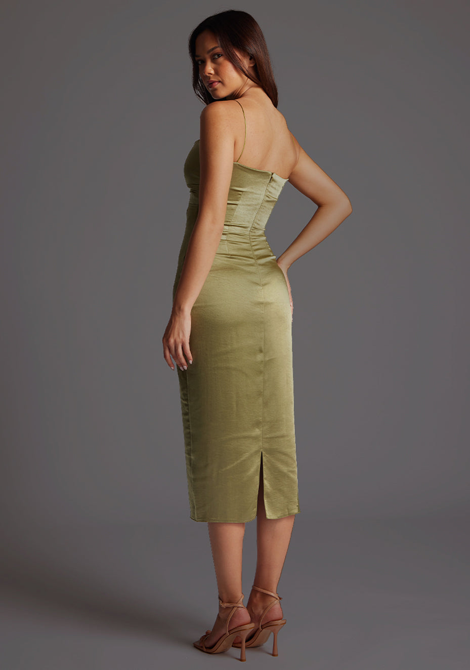 Back quarter image of a model wearing a olive midaxi dress with a delicate thin straps, a captivating twist and front cut-out design. The design featured is the Vesper Autumn Olive Midaxi Dress