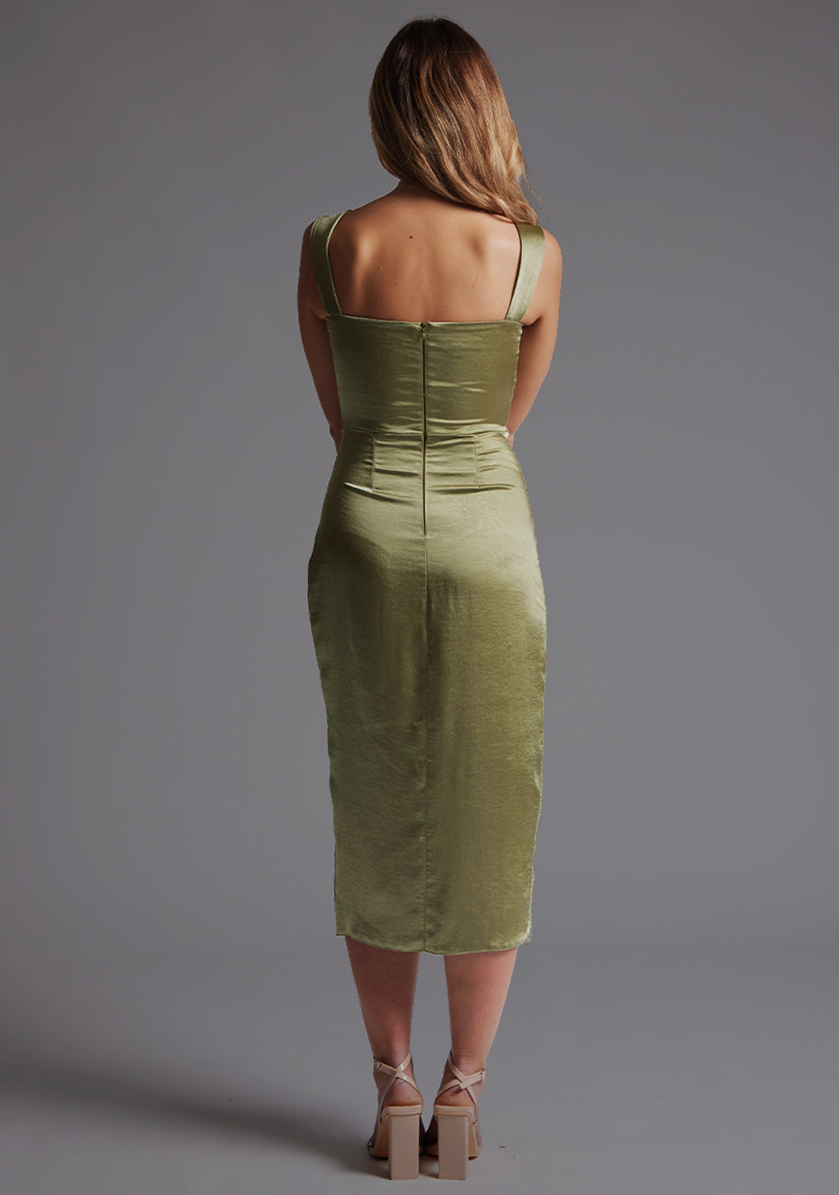 Back image of a model wearing olive satin midaxi dress with  a sweetheart neckline, wide comfy straps and front skirt split. The dress featured is the Vesper Desiree Olive Satin Midaxi Dress.