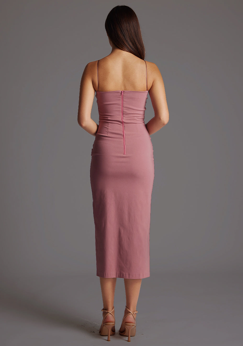 Back image of a model wearing a rose midaxi dress with a plunging neckline with thin straps, a front bodice cut-out and front skirt split. The design featured is the Vesper Martina Rose Midaxi Dress