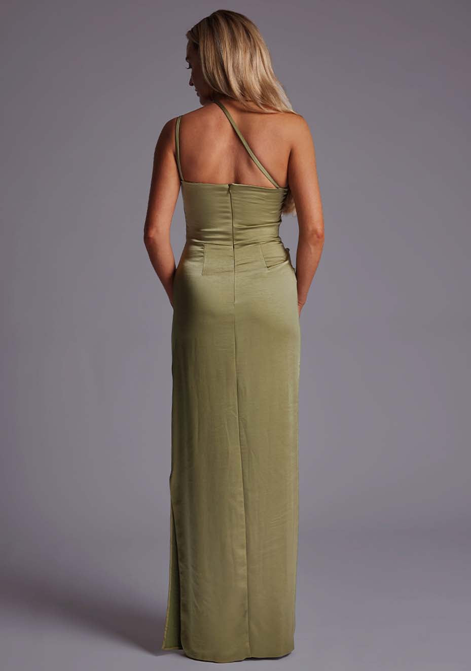 Back image of a model wearing an olive satin maxi dress with a cross strap detail, pleats detailing at the front bust and delicate side skirt split. The design featured is the  Vesper Solange Olive Satin Maxi Dress.