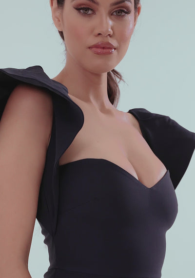 Model posing in the VSPR Sunday Frill Shoulder Midaxi Dress in navy, showcasing the sweetheart neckline, frill cap sleeves, and front skirt split. The midaxi dress flows elegantly with movement, highlighting its soft hem and sophisticated silhouette in a studio setting.
